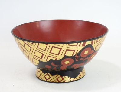 un bol rouge et jaune posé sur une surface blanche