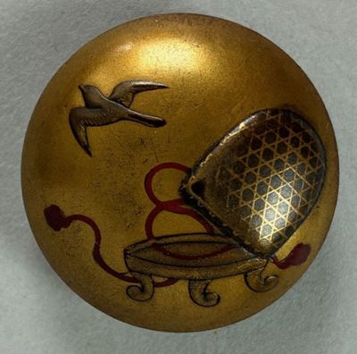 a gold ornament with a bird and a birdcage on it