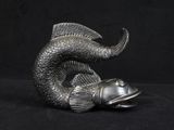 a silver fish statue on a black background