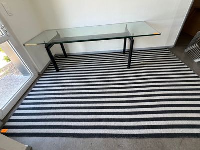 un tapis à rayures noires et blanches avec une table en verre