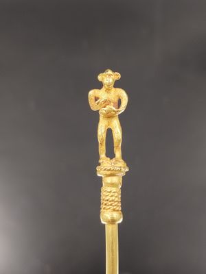une figurine en or représentant un homme tenant un poisson au bout d'un bâton