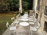 de nombreuses chaises et tables sur le trottoir devant un immeuble