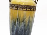 a yellow and blue vase sitting on a stand