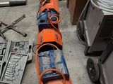 un long tuyau orange posé par terre à côté d'autres outils