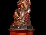 statue of a woman holding a child on a wooden base