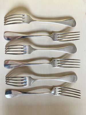 six forks are lined up in a row on a table
