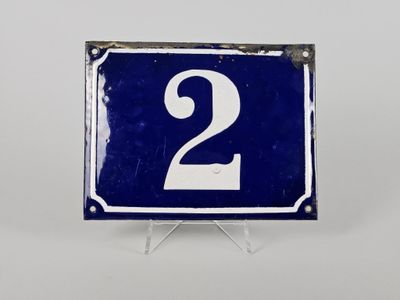 une vieille plaque de numéro de maison bleue et blanche sur laquelle figure le chiffre 2