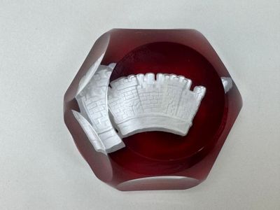 un bol en verre rouge orné d'un château blanc