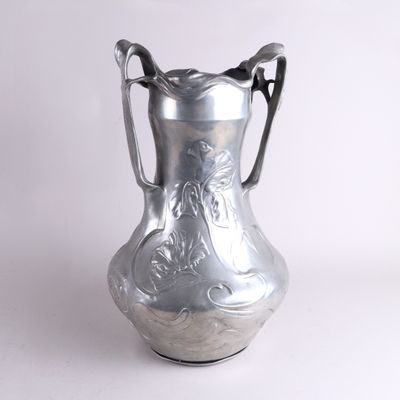 un vase en argent posé sur une surface blanche