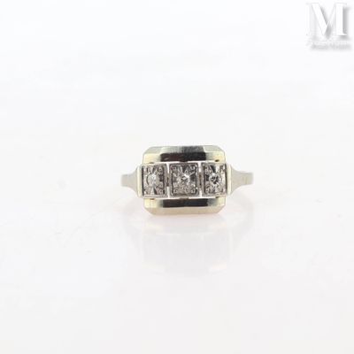 a close up of a ring with three diamonds on a white surface