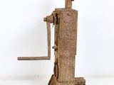 an old rusted metal machine with a wooden handle on a white surface