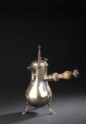 une cafetière ancienne en argent avec une poignée en bois, sur fond noir