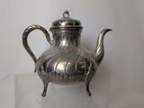 a silver tea pot sitting on a glass table