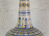 a blue and white vase with a yellow handle on a table
