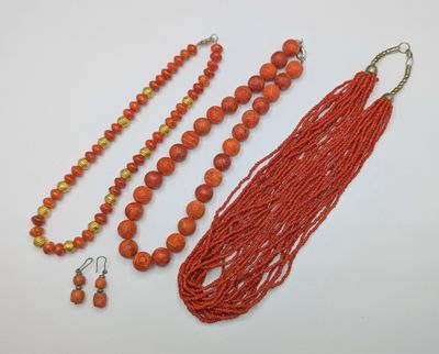 an assortment of orange beads and earrings on a white surface