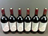 six bottles of red wine lined up in a row on a table
