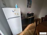 un réfrigérateur dans un coin d'une pièce où se trouvent une table et des chaises