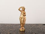 une statue en or représentant une femme, posée sur une table en marbre