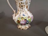 a white and gold vase with flowers painted on it