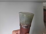 a person holding a small green vase in their hand