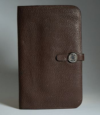 un gros plan d'un carnet en cuir marron muni d'un bouton sur la couverture