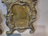 two ornate silver picture frames on a white table
