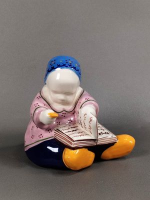 une figurine représentant une femme assise par terre en train de lire un livre
