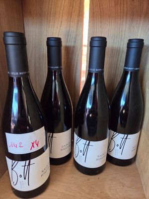quatre bouteilles de vin sont alignées sur une étagère