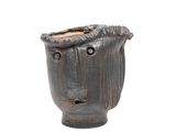 un vase noir orné d'un visage sur fond blanc