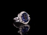 une bague ovale sertie d'un saphir bleu et de diamants, posée sur un fond noir