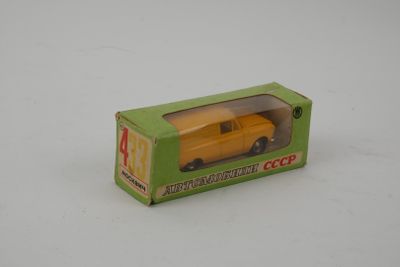 un camion jouet jaune dans une boîte verte posée sur une surface blanche