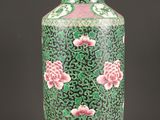 vase vert et rose avec des fleurs, posé sur un socle, sur fond noir