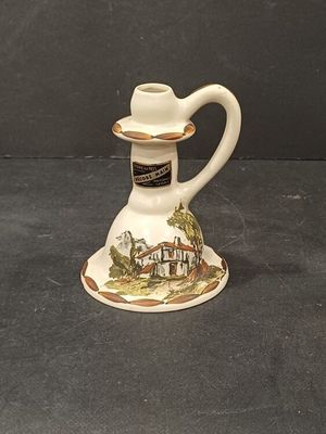 a small white pitcher with a picture of a house on it