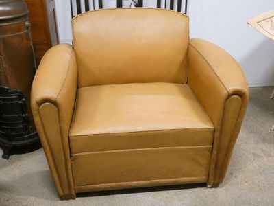 a tan leather chair sitting in the corner of a room