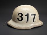 an old helmet with the number 377 on it sitting on a black surface