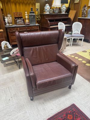 a brown leather chair in a living room with a rug on the floor