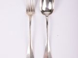 two silver spoons and a fork on a white surface