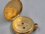 a gold pocket watch sitting on a white surface