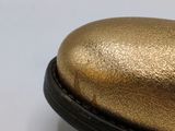 a close up of a gold shoe on a white surface