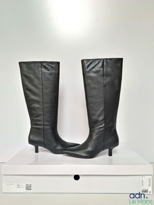 la paire de bottes en cuir noir repose sur une boîte blanche