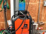 une soudeuse orange et noire posée dans un garage, à côté d'un tas d'outils