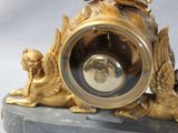 a gold clock with a bird on top of it on a marble base