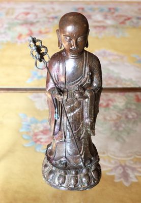 une statue représentant une personne tenant une fleur, posée sur une table