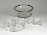 un bol en verre et un cendrier en verre posés sur une surface blanche