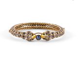 un gros plan sur un bracelet en or orné de pierres bleues et blanches