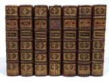 several old books are lined up in a row on a white surface