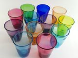many different colored glasses arranged in a circle on a white surface