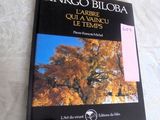 un livre posé sur un lit, avec l'image d'un arbre en arrière-plan