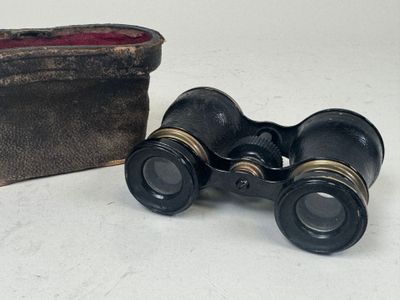 pair of binoculars sitting next to a wallet on a white surface