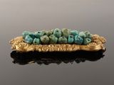an image of a gold plate with a bunch of turquoise beads on it